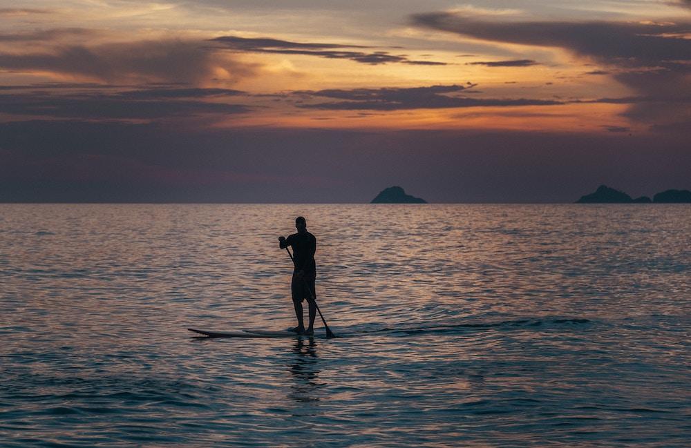 Someone paddle boarding on the sea at sunset