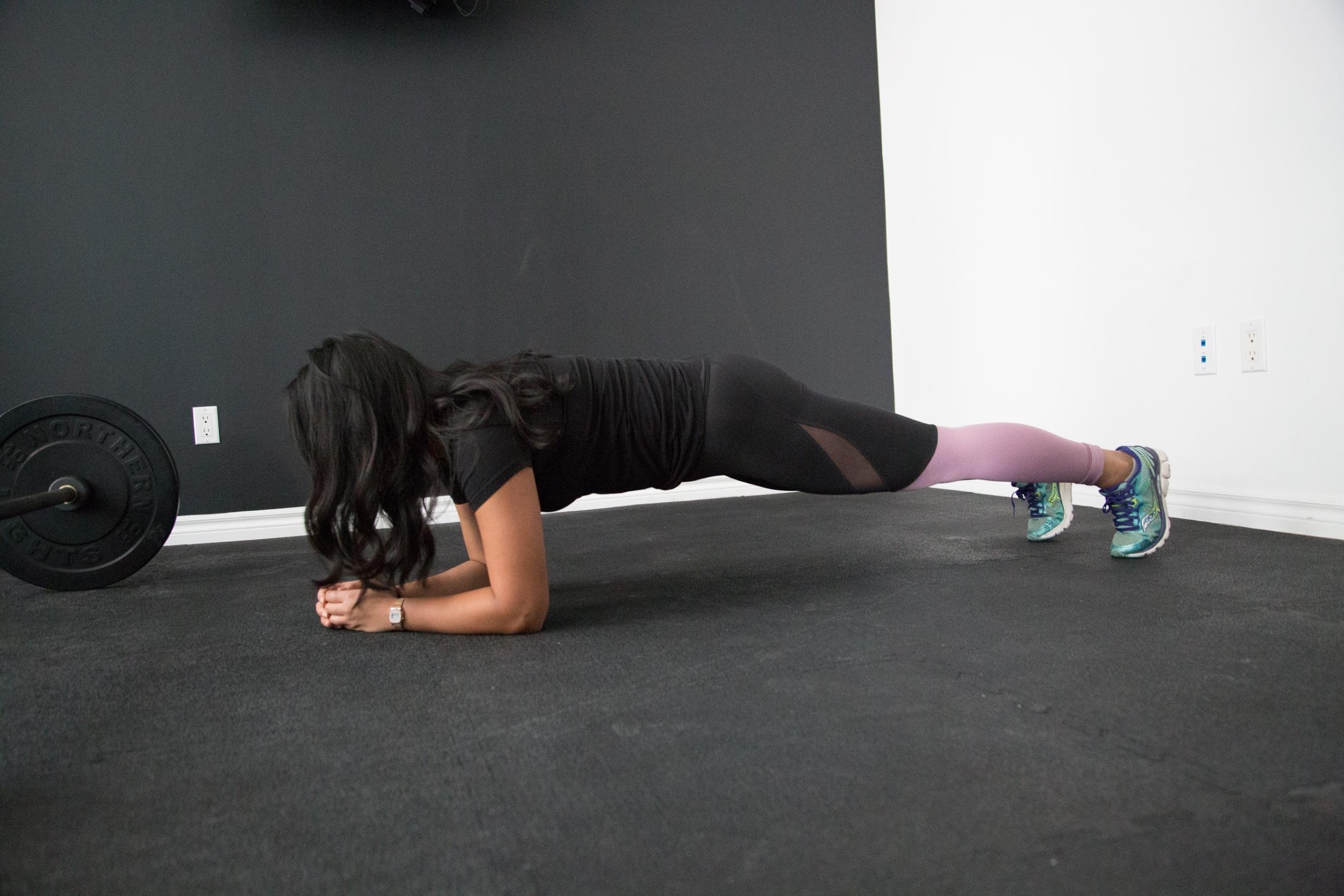 Woman doing plank exercise next to weights